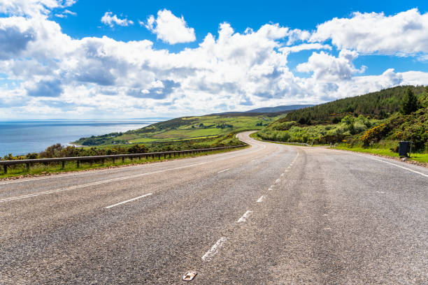 Large empty winding highway along the coast on a clear spring day. Scotland, UK.