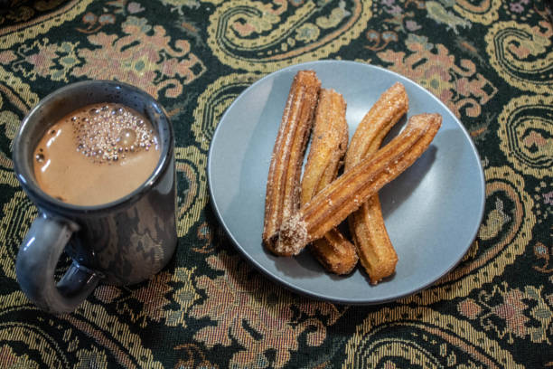 istock Hot  chocolate and churros for dinner in a grey plate and a green pattern tapestry  as background 1177121486