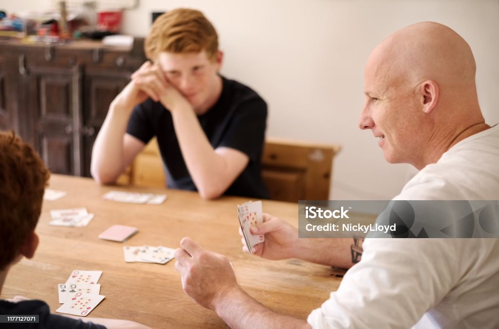 I need just one card for winning this hand Shot of a mature man playing cards with his boys at home Family Stock Photo