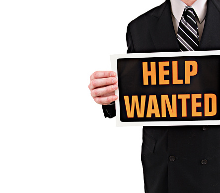 a businessman holding a help wanted sign isolated on white.