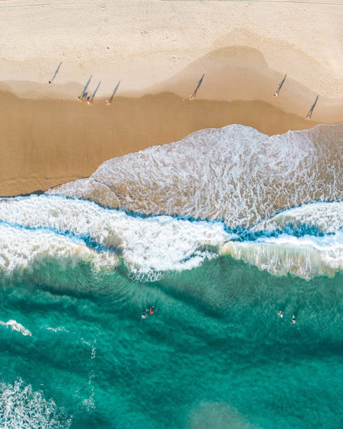 воздух людей, идущих по пляжу на восходе солнца с красивым песчаным пляжем и нежными волнами - pacific ocean фотографии стоковые фото и изображения