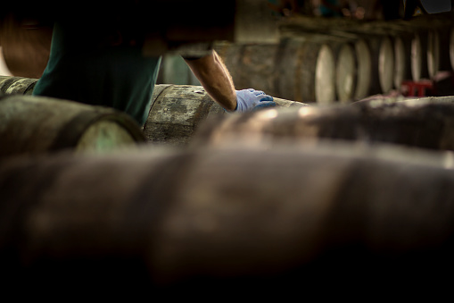 Man working between wooden barrels in a rum distillery.