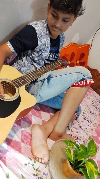 istock A Barefoot Young Boy in India Practices his Guitar in his Bedroom 1177141172