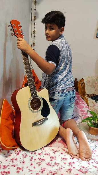 istock A Barefoot Young Boy in India Practices his Guitar in his Bedroom 1177141189