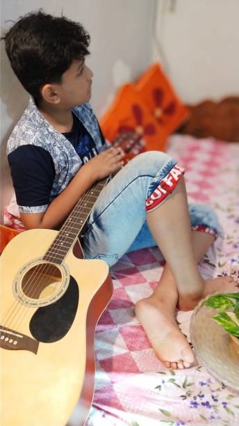 istock A Barefoot Young Boy in India Practices his Guitar in his Bedroom 1177141223