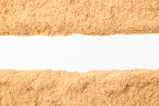 Overhead shot of border of sawdust on white background.