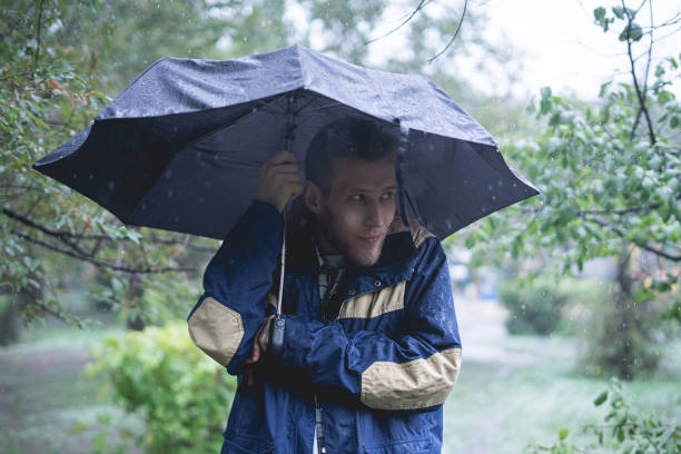 istock young man standing under the umbrella protect from heavy tropical rain in forest 1177154967