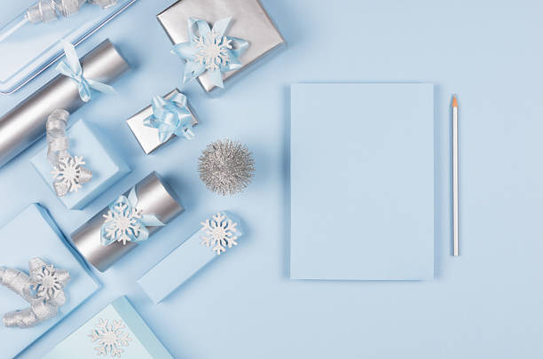 istock Modern soft minimalist christmas background with copy space for text and design - pastel blue empty paper, silver metallic gift boxes with shiny ribbons and bows, christmas tree on blue color backdrop, top view. 1177162075