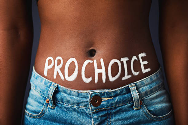 I have the final say Cropped studio shot of a woman with “pro choice” painted on her stomach against a dark background abortion photos stock pictures, royalty-free photos & images