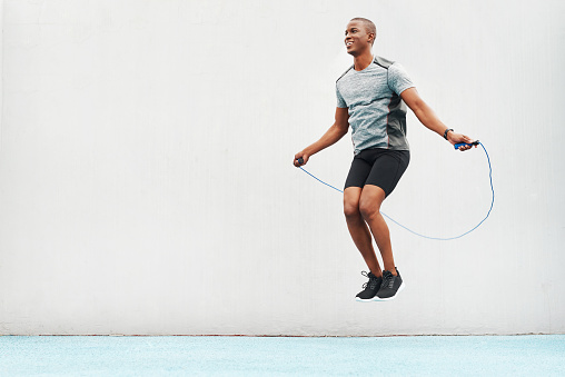 Full length shot of a handsome young athlete using a skipping rope during an outdoor training session