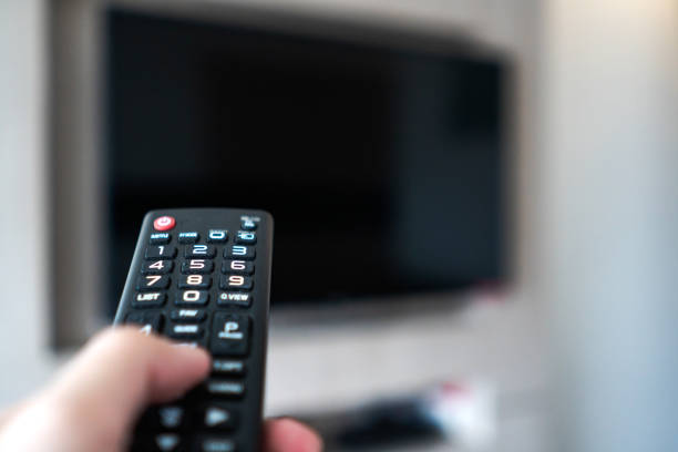 istock hand holding remote control point to television 1177167472