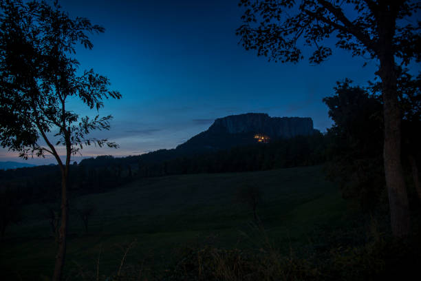 The stone of Bismantova, an isolated impressive spur in the italian appenines region. Blue hour, twilight view, framed by trees.