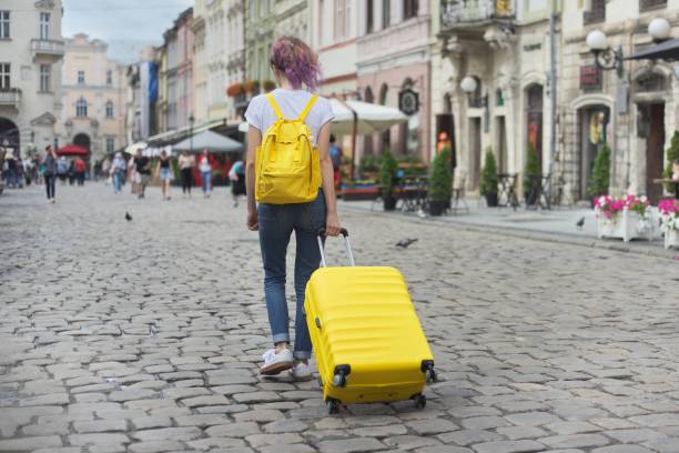 istock Traveler girl walking with backpack and yellow suitcase 1177173675