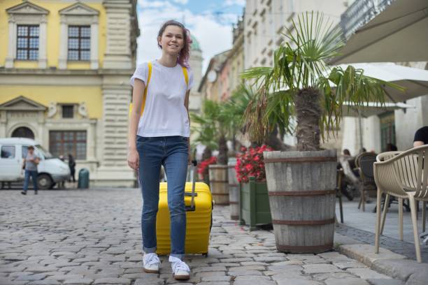istock Traveler girl walking with backpack and yellow suitcase 1177173711