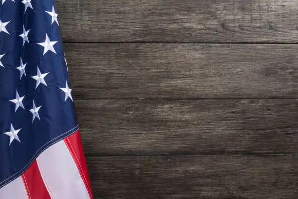 US flag with embossed stars, hanged against old wooden wall background