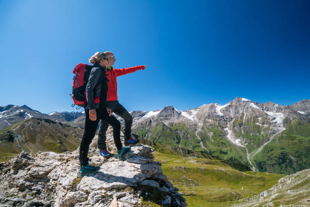 couples sportifs d'alpiniste restant sur la roche regardant les crêtes étonnantes de montagne haut dans les alpes - european alps mountain mountain peak rock photos et images de collection