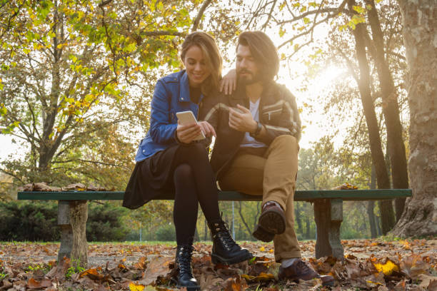 istock Young couple using cellphone in autumn colored park. 1177177346