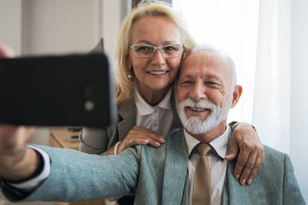istock Senior couple sitting on bed in room taking selfie 1177177517