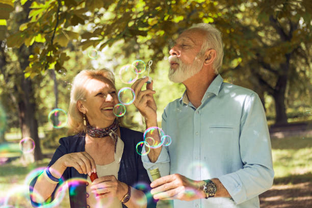 istock Elderly couple blowing bubbles in park 1177178487