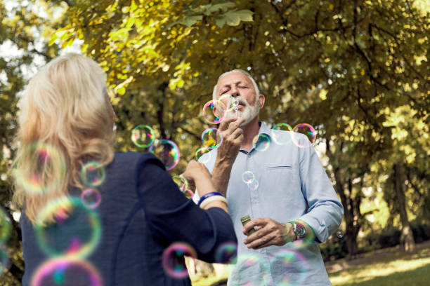 istock Elderly couple enjoying blowing bubbles in public park 1177178501