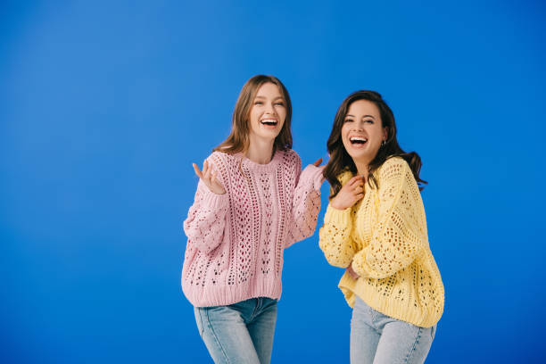 istock attractive and smiling women in sweaters looking at camera isolated on blue 1177185506