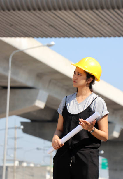 istock Female civil engineer or architect with yellow helmet, standing with project drafts while in hand. 1177186816