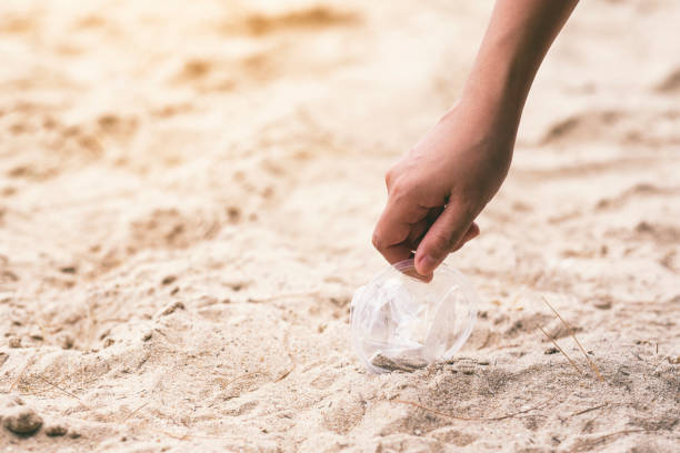 istock A hand picking up a plastic glass trash on the beach 1177188057