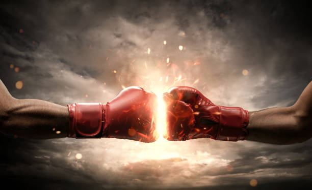 Conflict concept Boxing fight, close up of two fists hitting each other over dark, dramatic sky with copy space fighting stock pictures, royalty-free photos & images