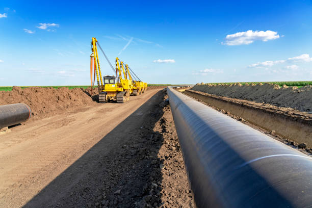 Pipeline Installation and Construction Heavy Machinery and Gas Pipeline Construction Site. Pipes are Laid on Top of Supportive Sandbags Beside Trench and Welded Together. pipeline stock pictures, royalty-free photos & images