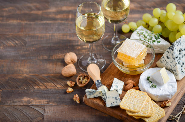 plato de queso con uvas, galletas, miel y nueces sobre una mesa de madera. - cheese still life tray french cuisine fotografías e imágenes de stock