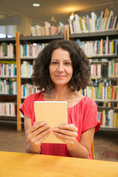 istock Happy female customer with gadget posing in public library 1177190747