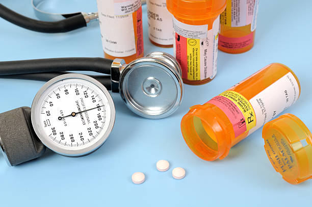 A stethoscope and blood pressure meter next to medication A blood pressure gauge showing high blood pressure, stethoscope, and medicine bottles, and pills. blood pressure medication stock pictures, royalty-free photos & images