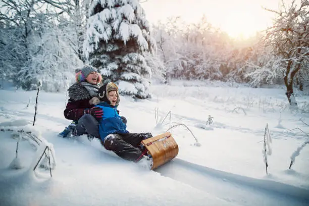 Little boy and his elder sister are tobogganing in forest. Kids are 12 and 8 years old.  Cold and sunny winter day.
Shot with Nikon D850