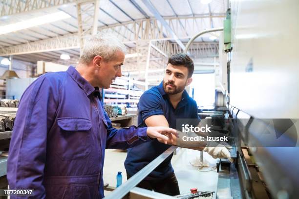 Engineers Discussing Over Machinery In Industry Stock Photo - Download Image Now - Trainee, Engineer, Manufacturing