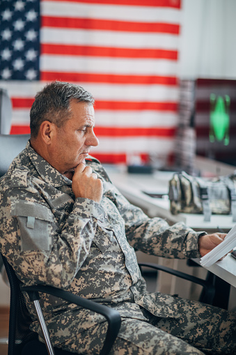 One mature man, American soldier sitting in headquarters office alone.