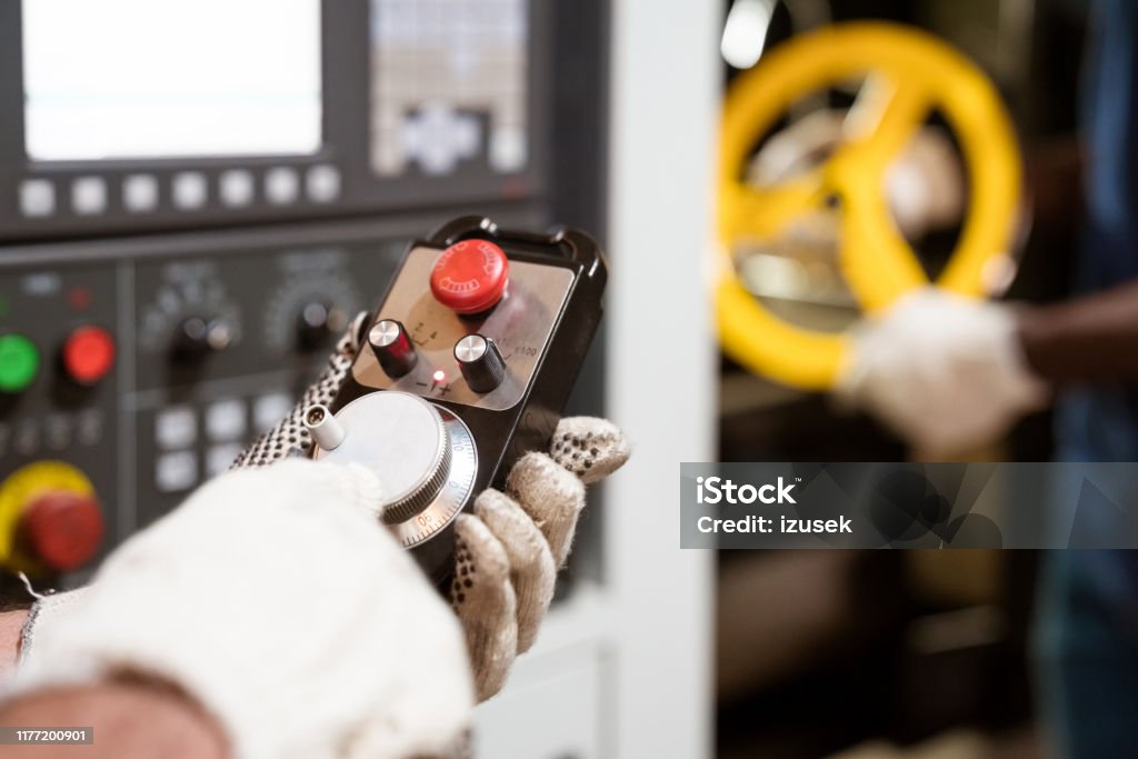 Manual worker wearing gloves using lathe machine Cropped image of manual worker turning knob. Male engineer is using lathe machinery. He is wearing protective gloves. Human Hand Stock Photo