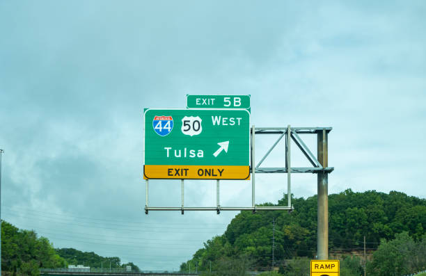 Oklahoma highway, USA. May 29, 2019: Exit to Tulsa road sign green color billboard on the highway, blue cloudy sky