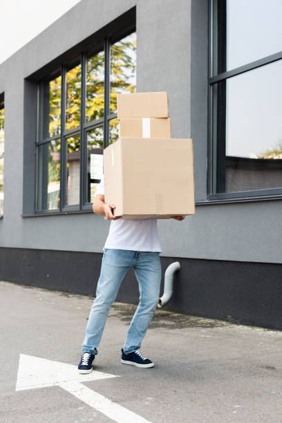 istock delivery man covering face while holding packages near building 1177203976
