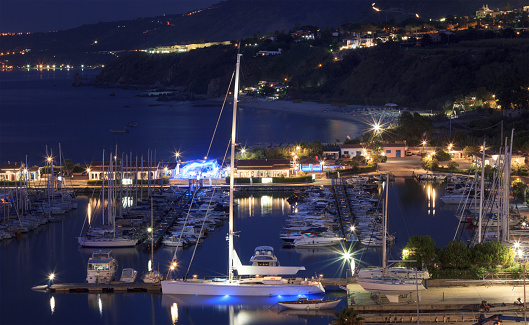Tropea, Italy - September 6, 2019: Panorama of Tropea yacht sea port with beautiful night colorful lights. Night illumination of Tropea city, Calabria