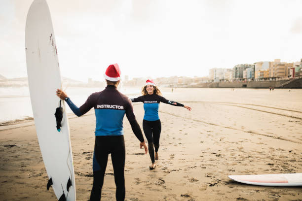 istock Two surf instructors couple on the beach with their surfboard 1177211083