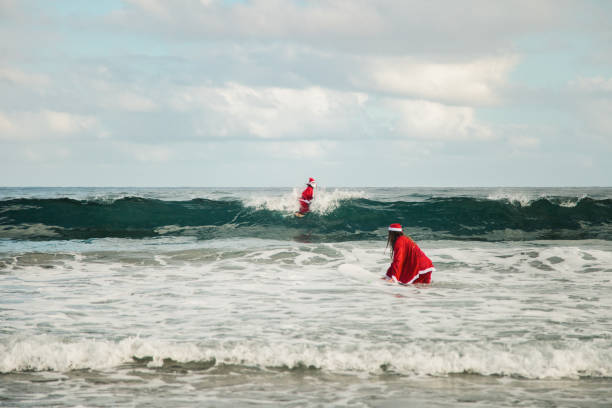 istock two surfers dressed as Santa Claus on the beach 1177211135