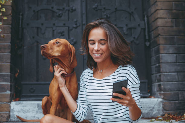 istock Young woman using smartphone with her dog in the backyard 1177211467