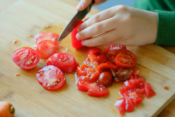 istock girl slices tomatoes to make a salad. 1177213724