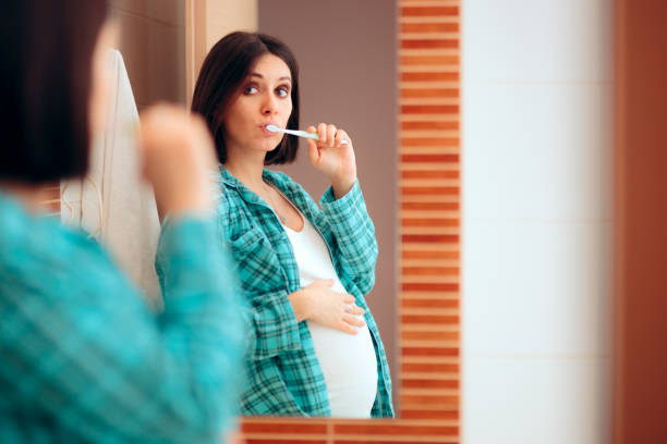 donna incinta che indossa il pigiama lavandosi i denti - healthy lifestyle toothbrush caucasian one person foto e immagini stock