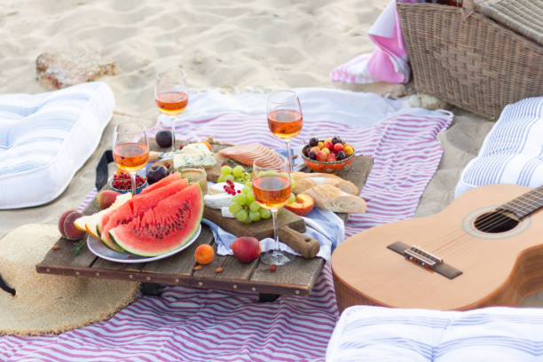 pique-nique de coucher du soleil par la mer. - beach table peach fruit photos et images de collection