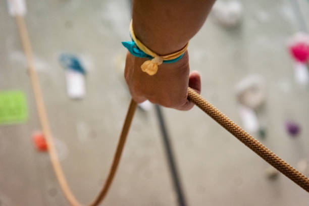 A rope is laying on the ground in a field. The rope is brown and is twisted. The grass is dry and brown