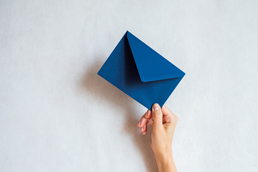 Woman holds in hand paper envelope. New mail, message. Postal service. Young girl want send or receive letter. Blank envelope, empty space. People communication concept. Envelope mockup closeup