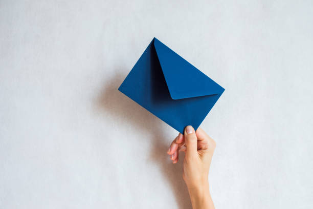 Woman holds in hand paper envelope. New mail, message. Postal service. Young girl want send or receive letter. Blank envelope, empty space. People communication concept. Envelope mockup closeup stock photo