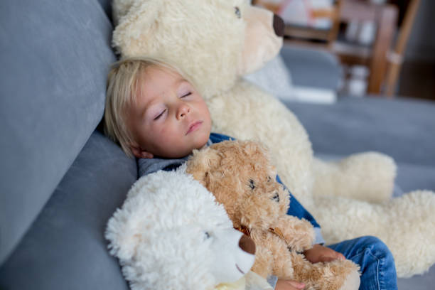 istock Blond toddler boy, sleeping with many teddy bears in the afternoon 1177222936