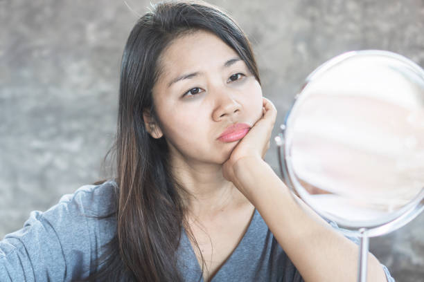 istock unhappy Asian woman age 40 checking her dark eyes circle problem in mirror 1177223439